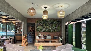 A modern interior with wicker furniture, a wooden table, and a green wall with plants. - Le Park 23 Boutique Resort (Roi Et)