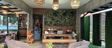 Un interior moderno con muebles de mimbre, una mesa de madera y una pared verde con plantas.