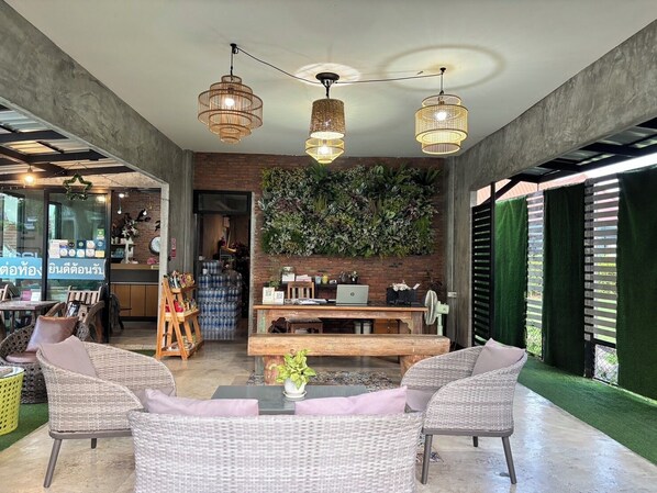 Un interior moderno con muebles de mimbre, una mesa de madera y una pared verde con plantas.