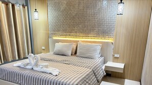 A hotel room with a bed, a nightstand, a wall-mounted lamp, and a decorative wall panel. - Le Park 23 Boutique Resort (Roi Et)