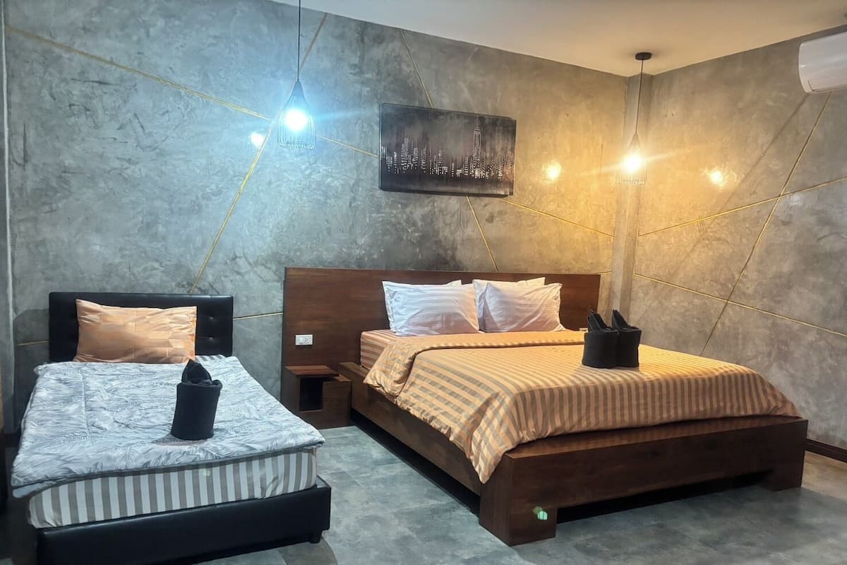 A modern hotel room with two beds, a cityscape artwork on the wall, and a unique lighting design.