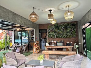 A modern interior with wicker furniture, a coffee bar, and a green wall with plants. - Le Park 23 Boutique Resort (Roi Et)