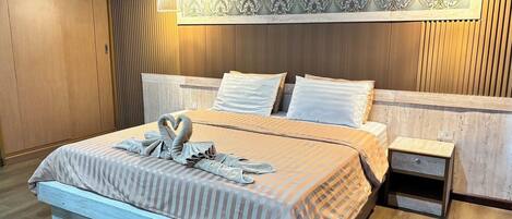 A neatly made bed with a striped bedspread and two pillows, a bedside table with a lamp, and a decorative wall panel above the bed.