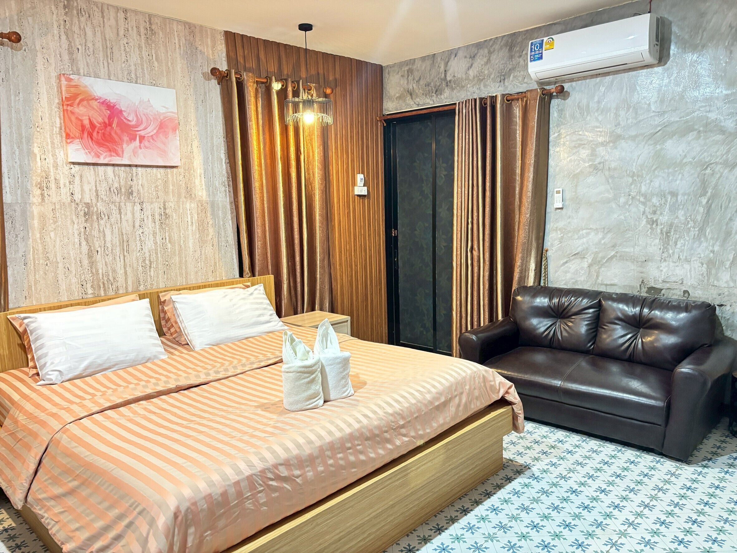 Una habitación de hotel con una cama, un sofá de cuero, un aire acondicionado instalado en la pared y una cortina.