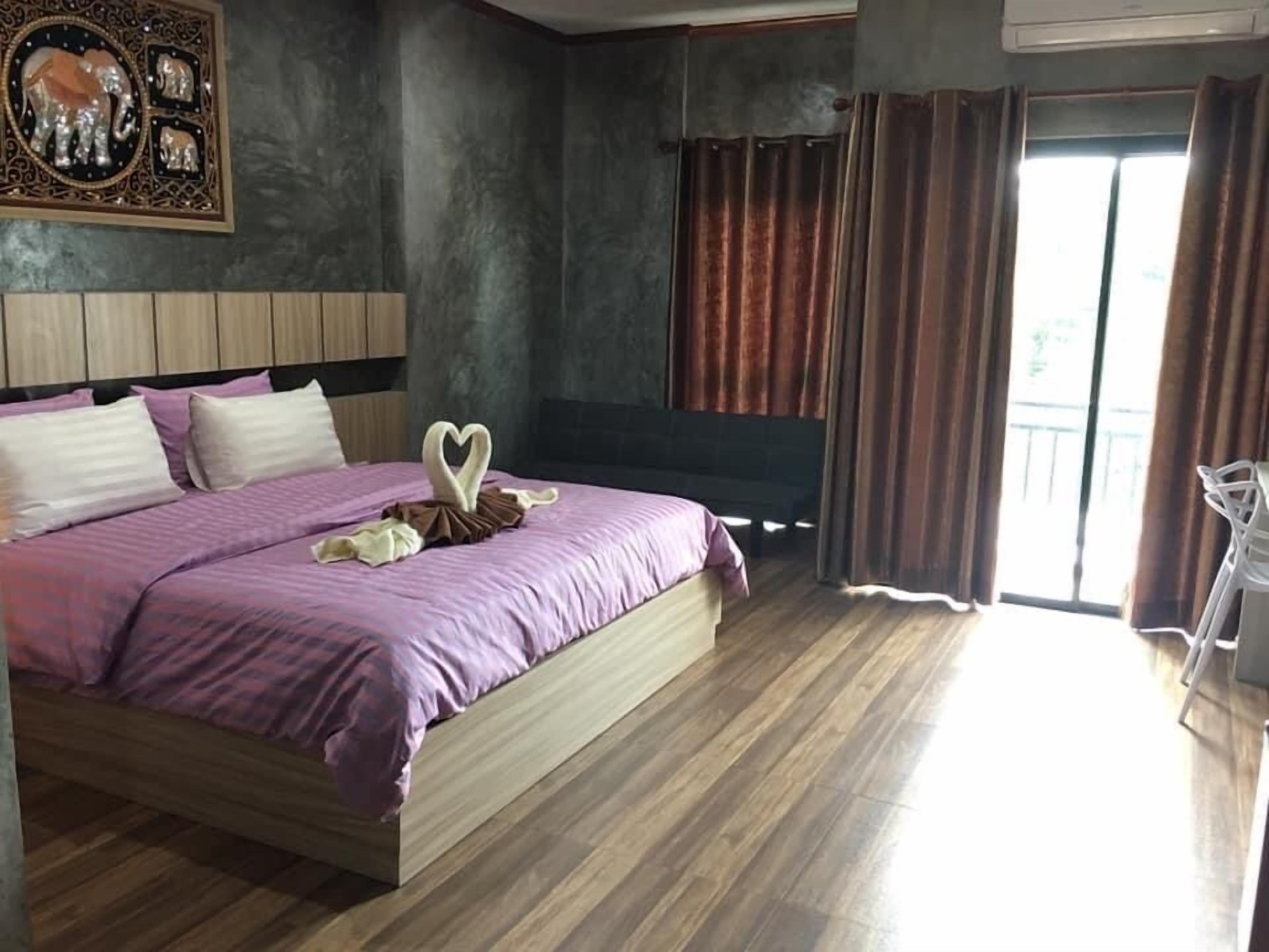 Ein modernes Schlafzimmer mit einem großen Bett, einem Flachbildfernseher und einem Balkon mit Vorhängen.