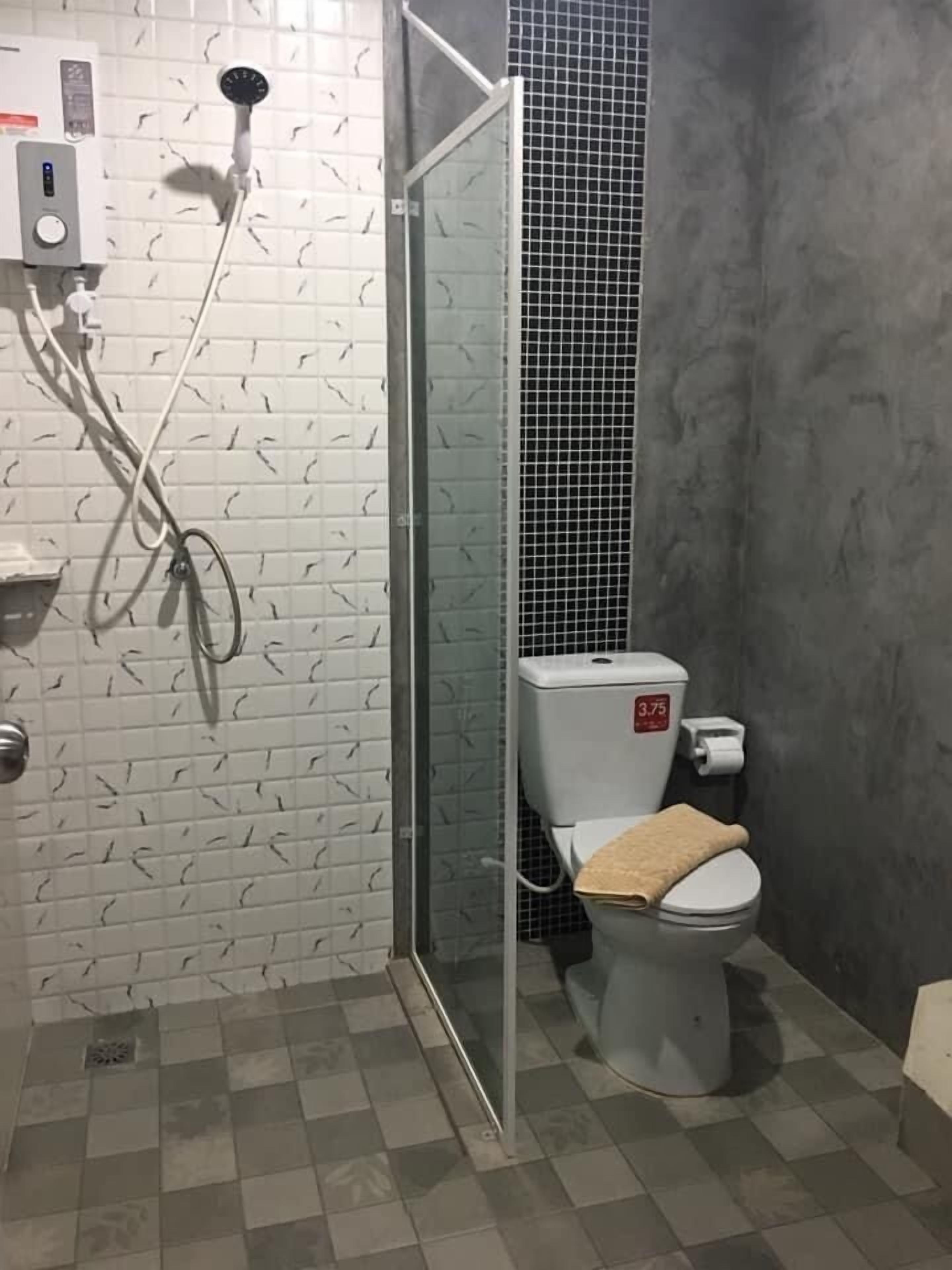 A bathroom with a shower, toilet, and a tiled wall.