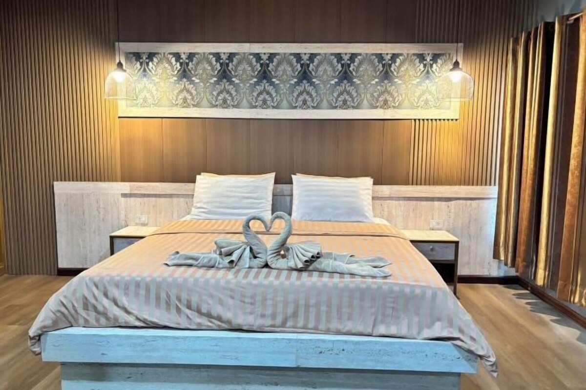 A hotel room with a large bed, a headboard with a patterned design, and a bedside table.