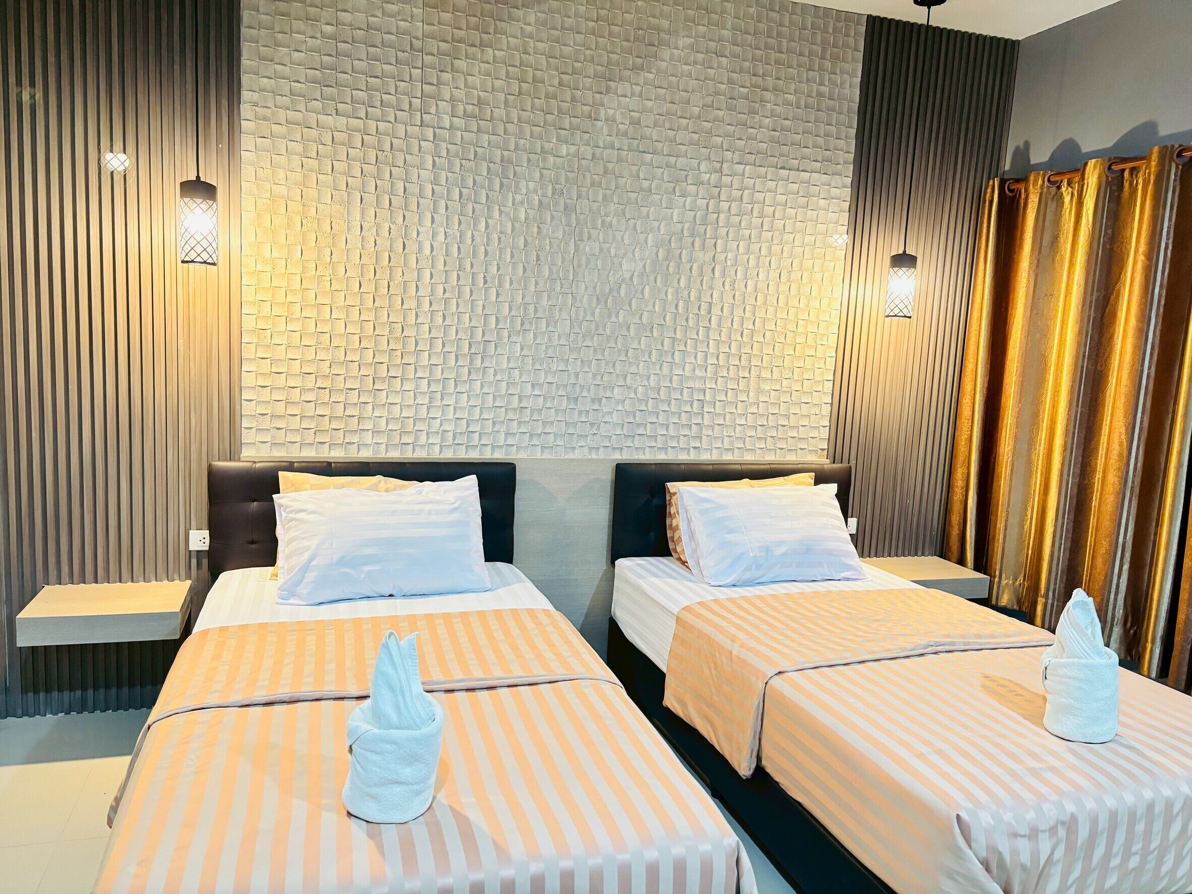 A hotel room with two beds, a brick-patterned wall, and a curtain.