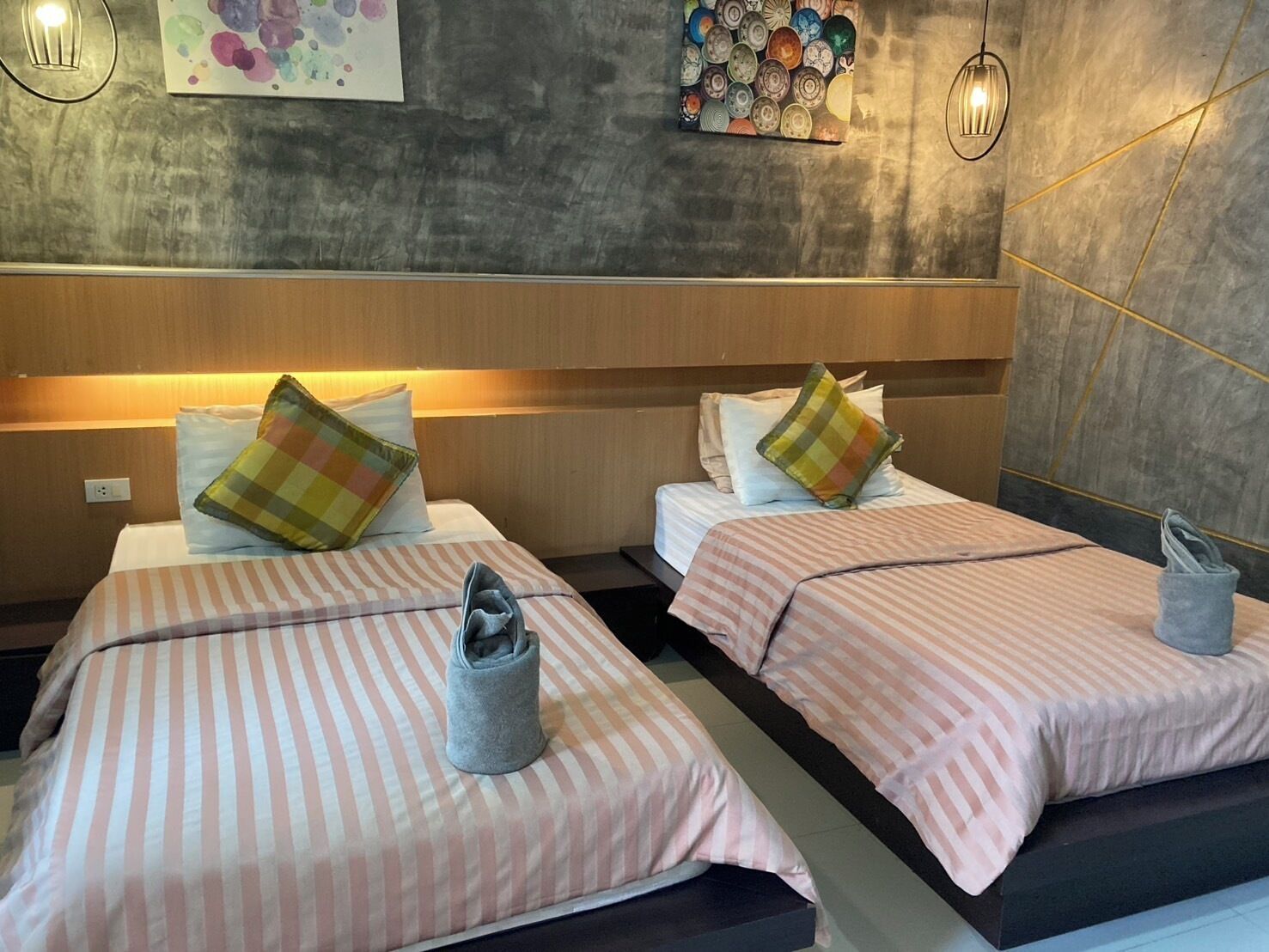 Habitación de hotel con dos camas, ropa de cama a rayas y un diseño moderno.