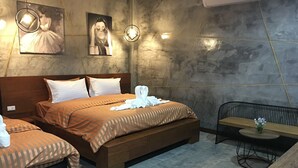 A hotel room with two beds, a wooden headboard, a small table with a vase, and a chair. - Le Park 23 Boutique Resort (Roi Et)