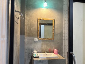 A bathroom with a white sink, a mirror with a gold frame, and a light fixture above the mirror. - Le Park 23 Boutique Resort (Roi Et)