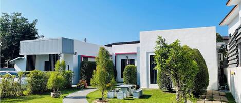 A modern house with a paved driveway, a small garden with a pathway, and a car parked in the driveway.