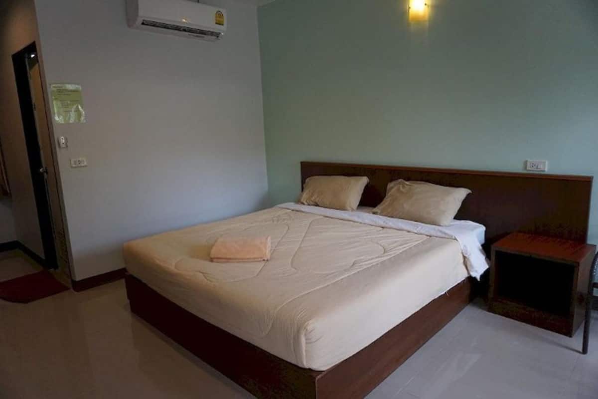 A hotel room with a bed, a nightstand, and an air conditioning unit.