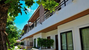 Um hotel moderno de vários andares com varandas, janelas amplas e um jardim bem cuidado.