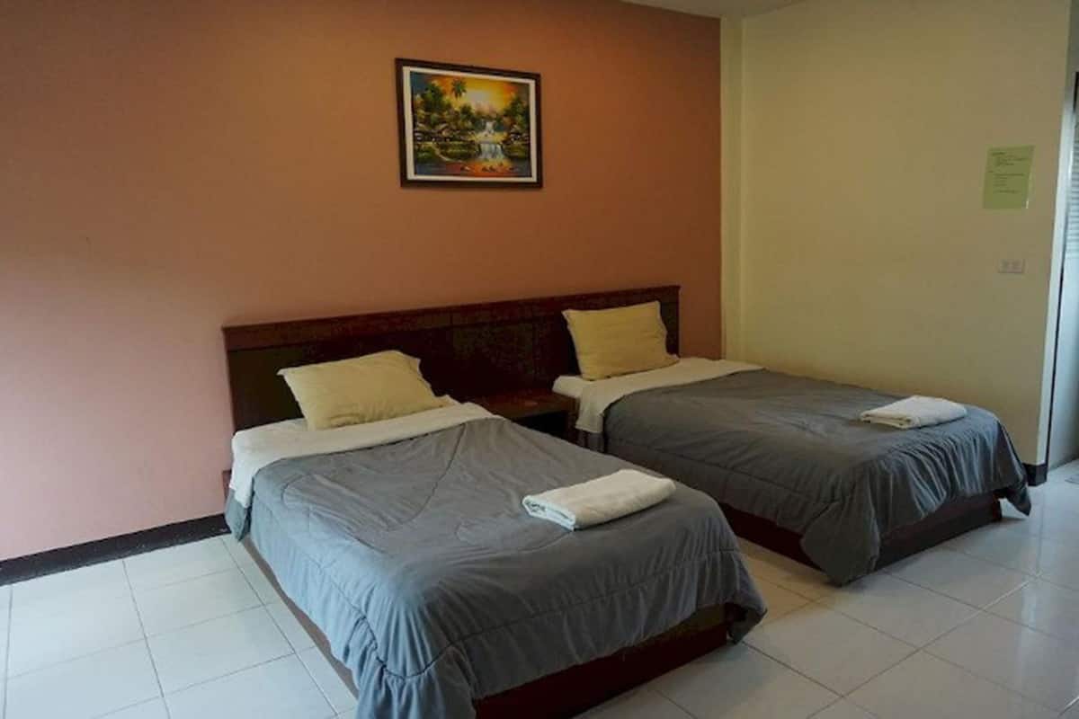 A hotel room with two single beds, a wooden headboard, and a painting on the wall.