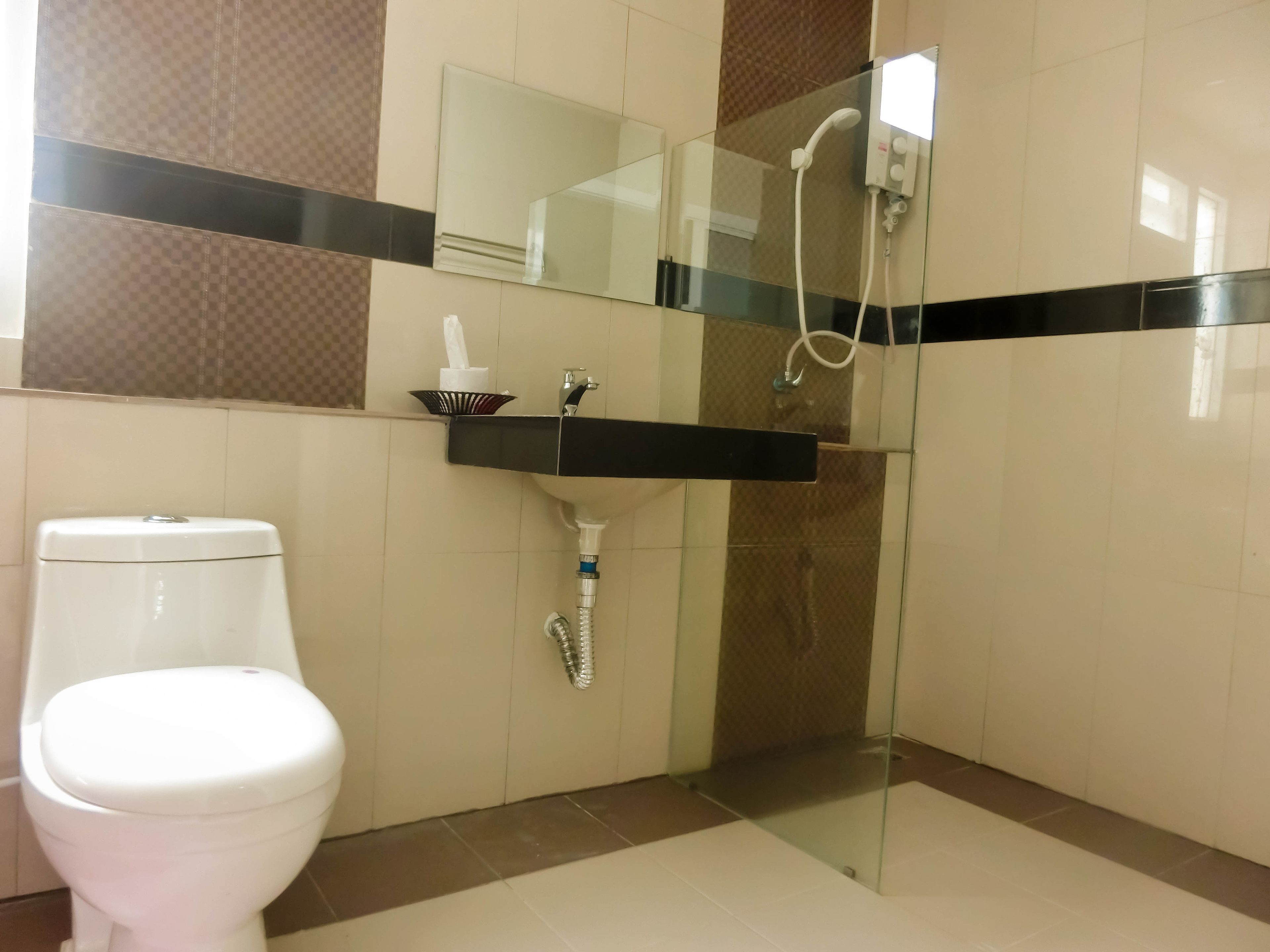 Un bagno con il water, una doccia vetrata e un lavandino con erogatore di asciugamani.