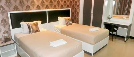 A hotel room with two beds, a desk, and a mirror.