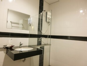 A modern bathroom with a glass-enclosed shower, a black countertop sink, and a mirror above it. - The Premium Residence (Roi Et)