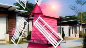 Un molino rosa con aspas blancas en una zona residencial.