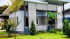 Una casa moderna de dos pisos con techo plano, ventanas amplias y un césped cuidado.