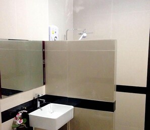 A bathroom with a white sink, a mirror, and a shower. - The Premium Resort (Suwannaphum)