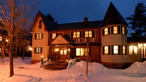 A large, two-story building with a prominent entrance, multiple windows, and a snow-covered ground. - PENSION & TRATTORIA Syo (Hakuba)