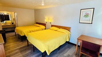 A hotel room with two beds, a wooden desk, a mirror, and a framed picture on the wall.