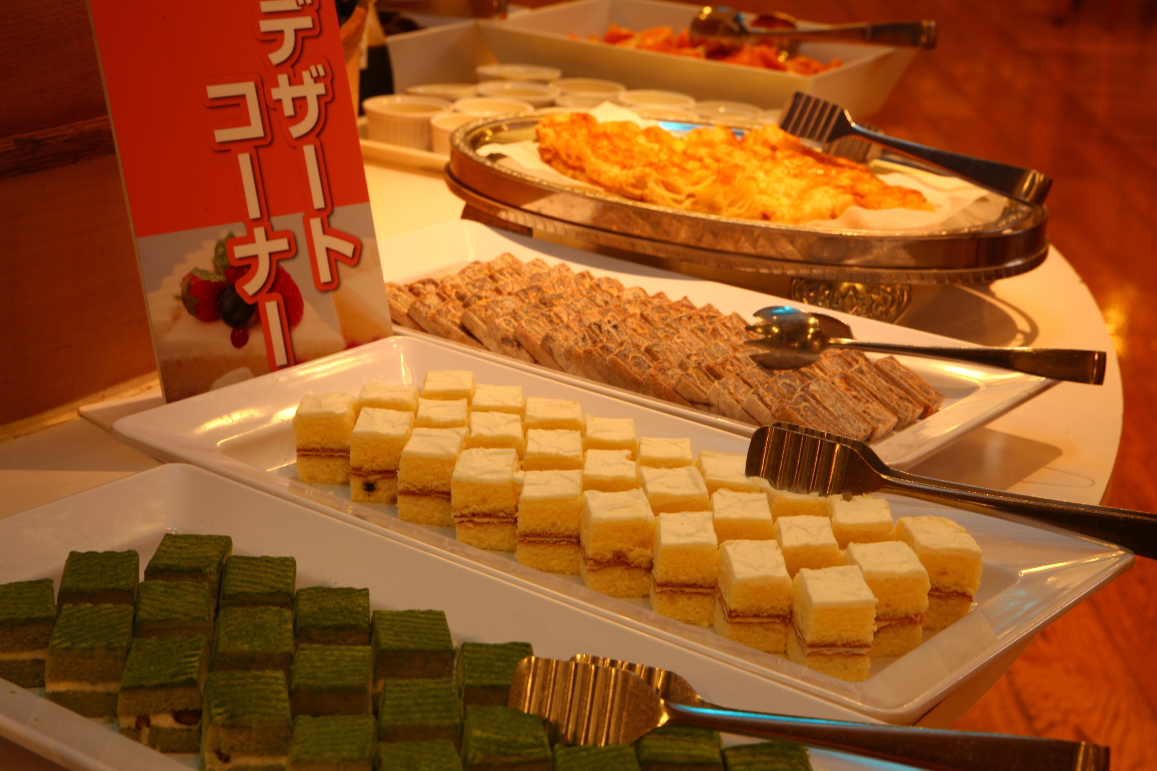 A buffet with various desserts and a sign with Japanese text.