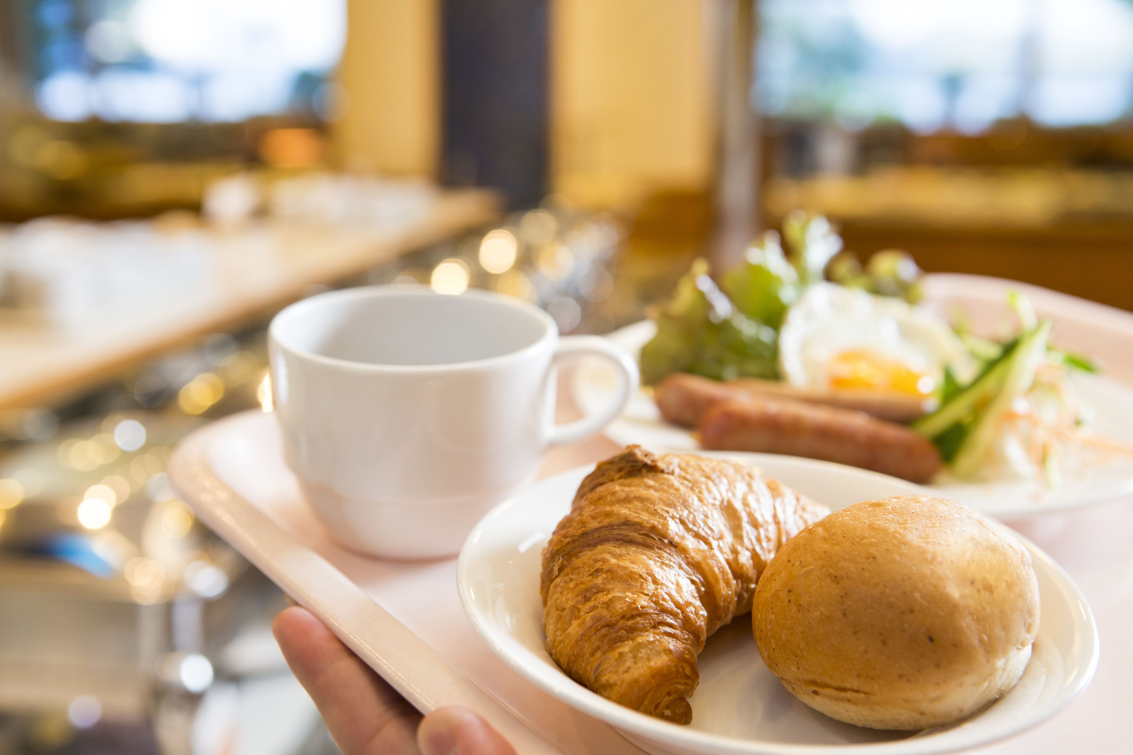 A tray with a croissant, a small round bread, and a cup of coffee.