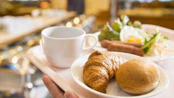 A tray with a croissant, a small round bread, and a cup of coffee.