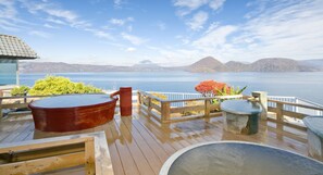 A wooden deck with hot tubs and a view of a lake and mountains. - Toya Kohantei (Toyako)