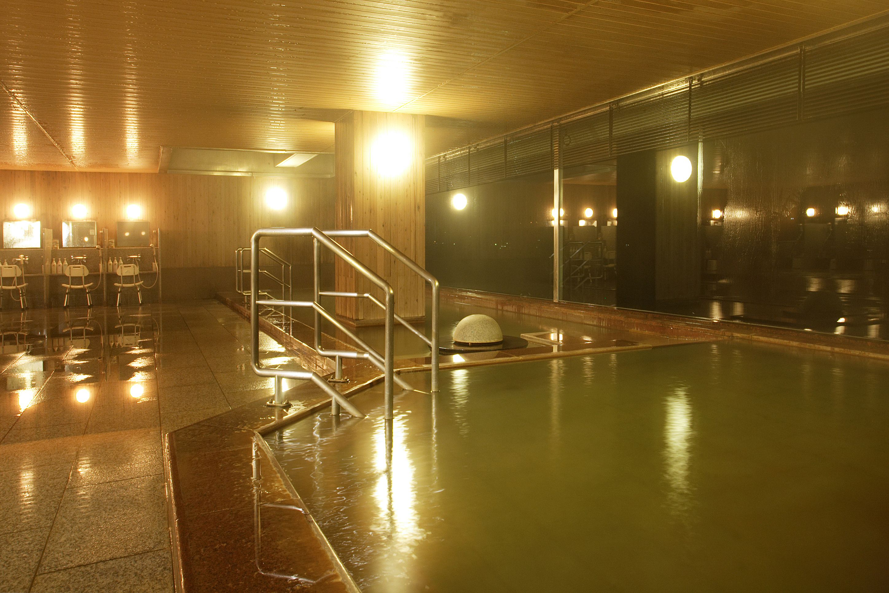 Una piscina con barrera de vidrio y una banca sumergida.