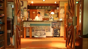 A reception area with a wooden counter, a sign reading "FRONT", and a menu board. - Pension ULLR (Hakuba)