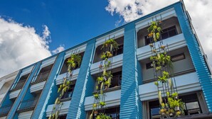 A multi-story building with balconies adorned with hanging plants. - Amity Poshtel - Hostel (Krabi)