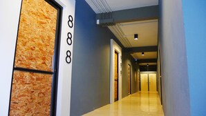A modern hotel hallway with a wooden wall on the left, numbered doors, and a blue wall on the right. - Amity Poshtel - Hostel (Krabi)