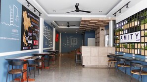 A modern bar area with a wooden counter, bar stools, and a ceiling fan. - Amity Poshtel - Hostel (Krabi)