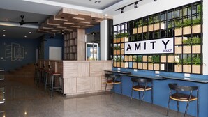 A modern bar area with a wooden counter, bar stools, and a wall-mounted plant display. - Amity Poshtel - Hostel (Krabi)