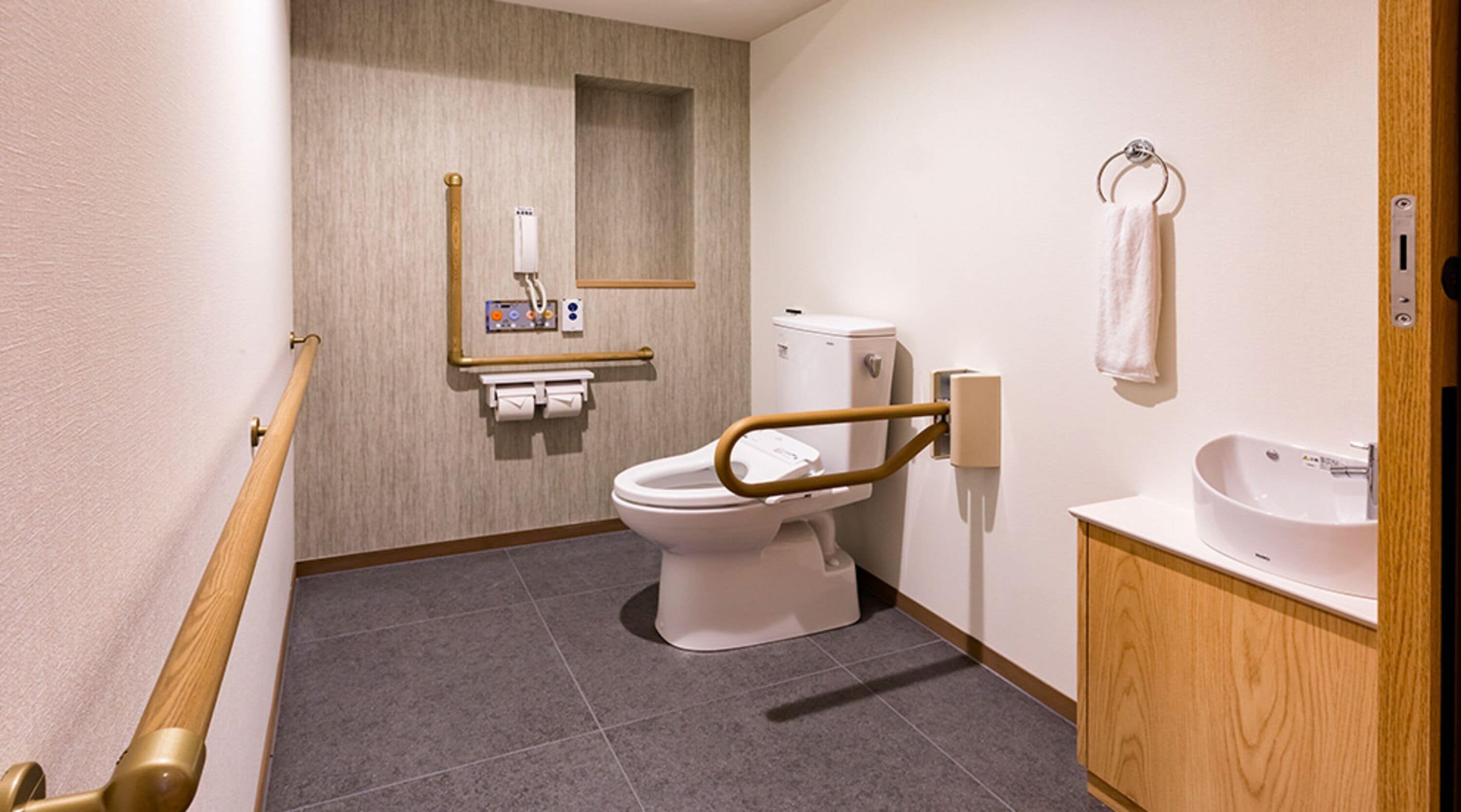 A modern bathroom with a toilet, hand sanitizer dispenser, and a sink.