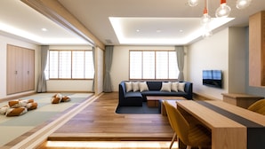 A modern living room with a sectional sofa, a dining table, and a TV mounted on the wall. - Kitayuzawa Mori no Soraniwa (Date)