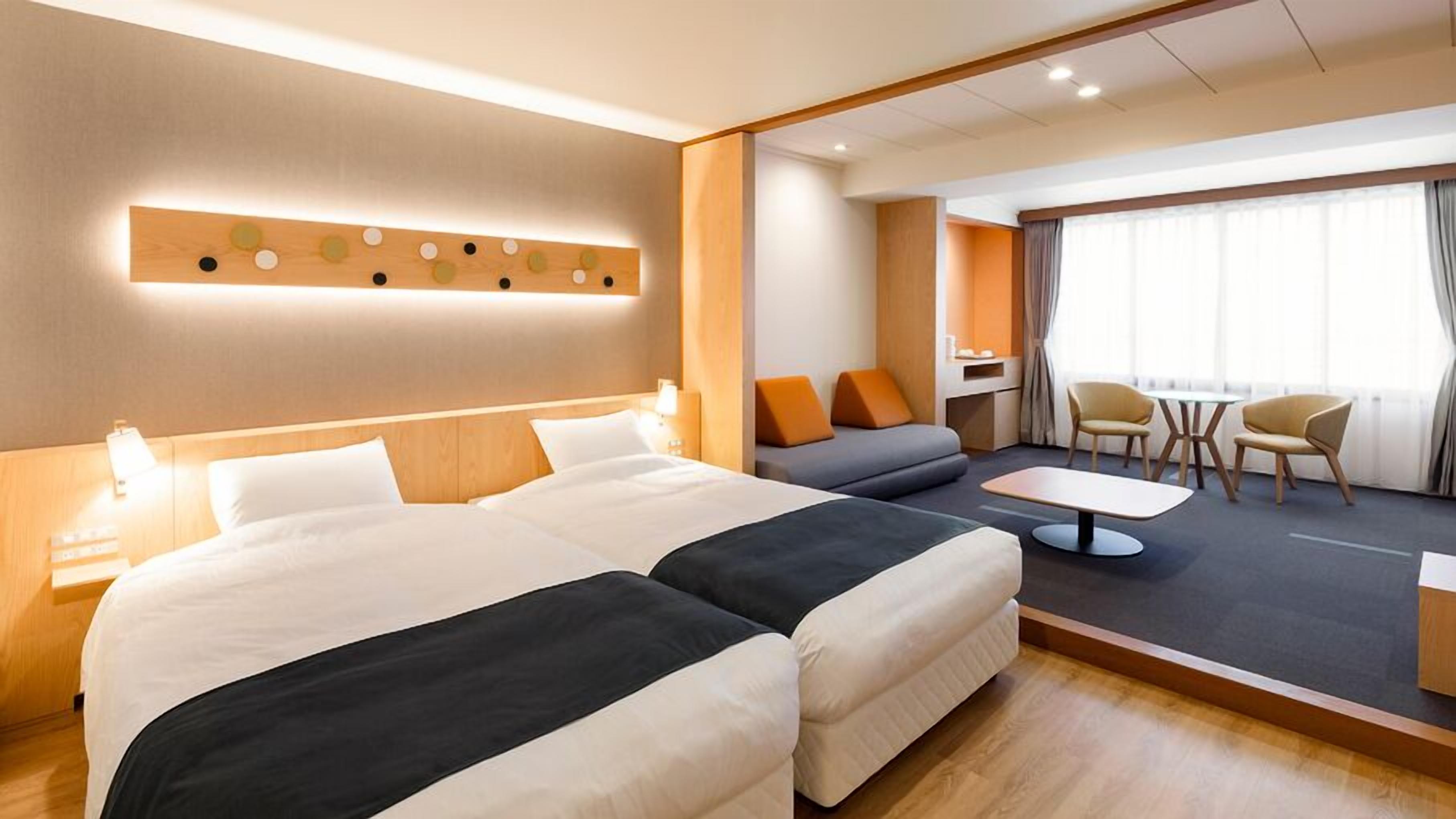Een hotelkamer met een groot bed, een bank, een kleine tafel en een zithoek met stoelen.