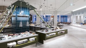 A modern hotel lobby with a central buffet area, multiple seating arrangements, and large windows providing natural light. - Kitayuzawa Mori no Soraniwa (Date)
