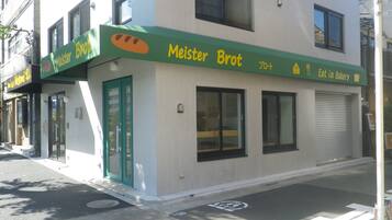 Een bakkerij genaamd 'Meister Brot' met een groen luifel, een duidelijke deur en ramen.