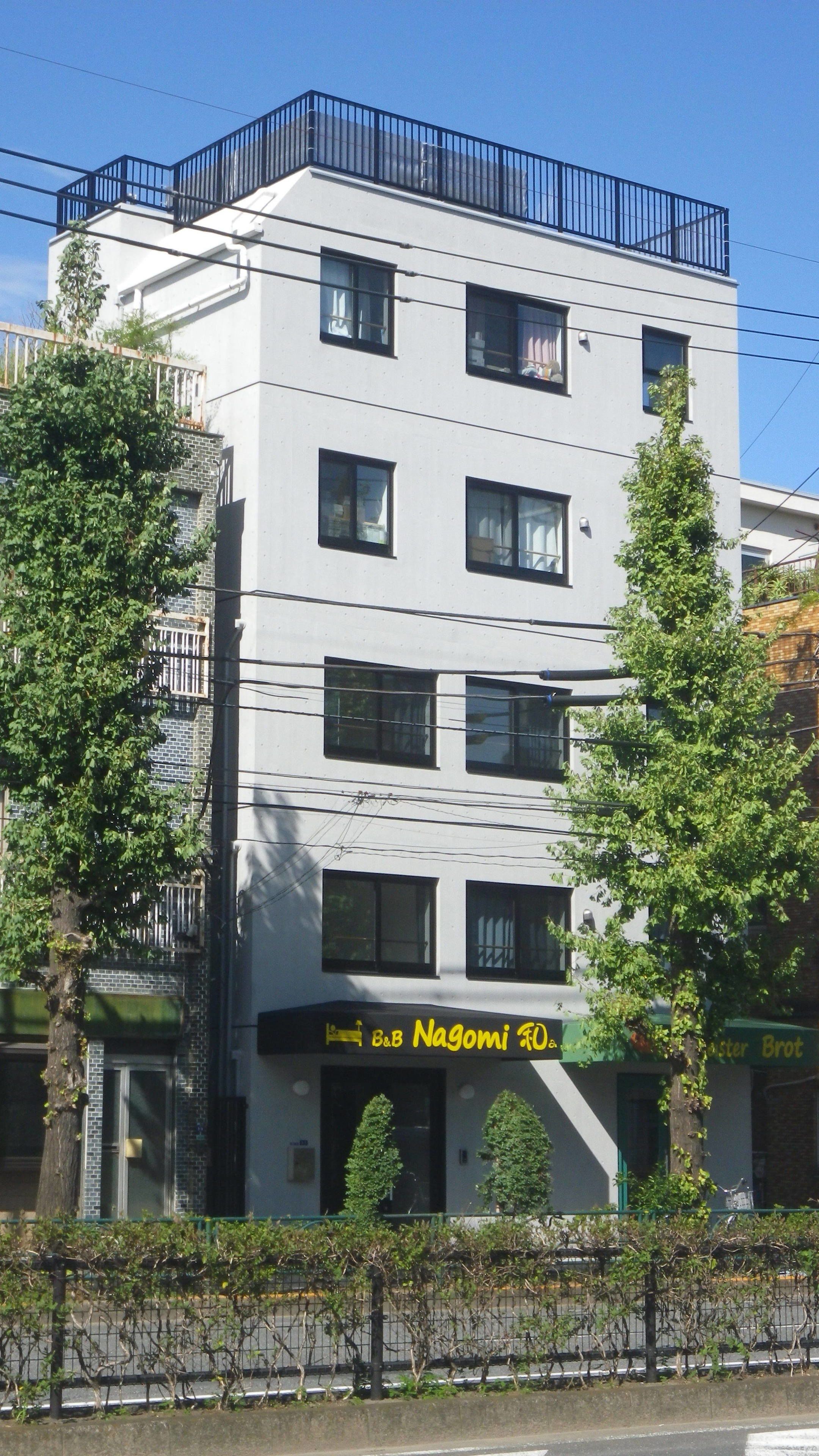 A modern building with multiple windows and a sign for 'B&B Nagomi'.