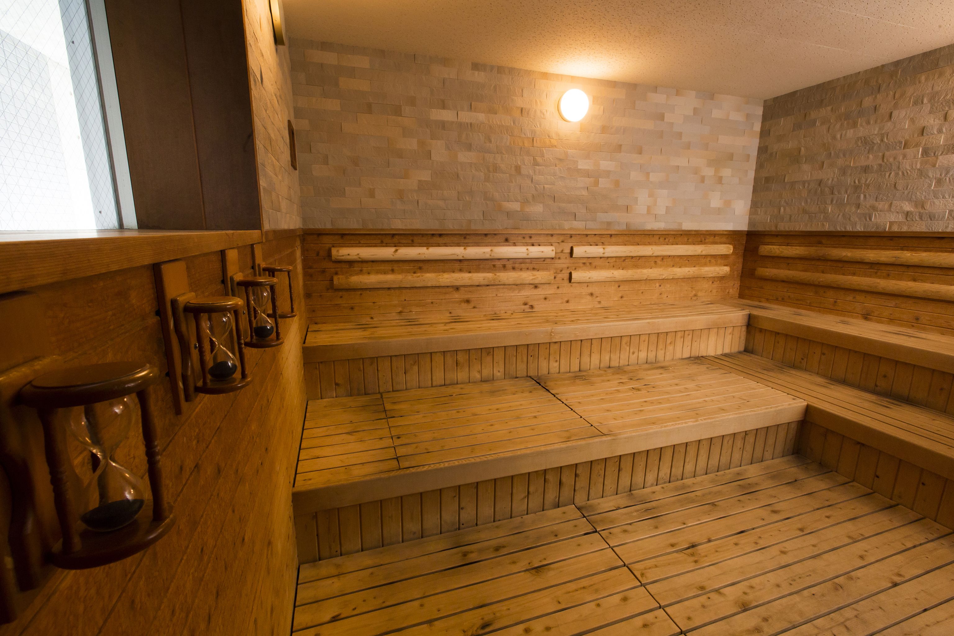 Una sauna con bancos de madera y pared de azulejos.