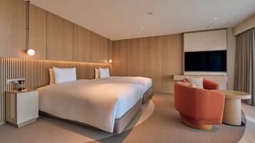 Ein modernes Hotelzimmer mit einem großen Bett, einer Sitzecke mit einem roten Sessel, einem kleinen Tisch und einem an der Wand montierten Fernseher.