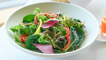 A bowl of mixed greens salad with various vegetables like broccoli, red onions, and leafy greens.