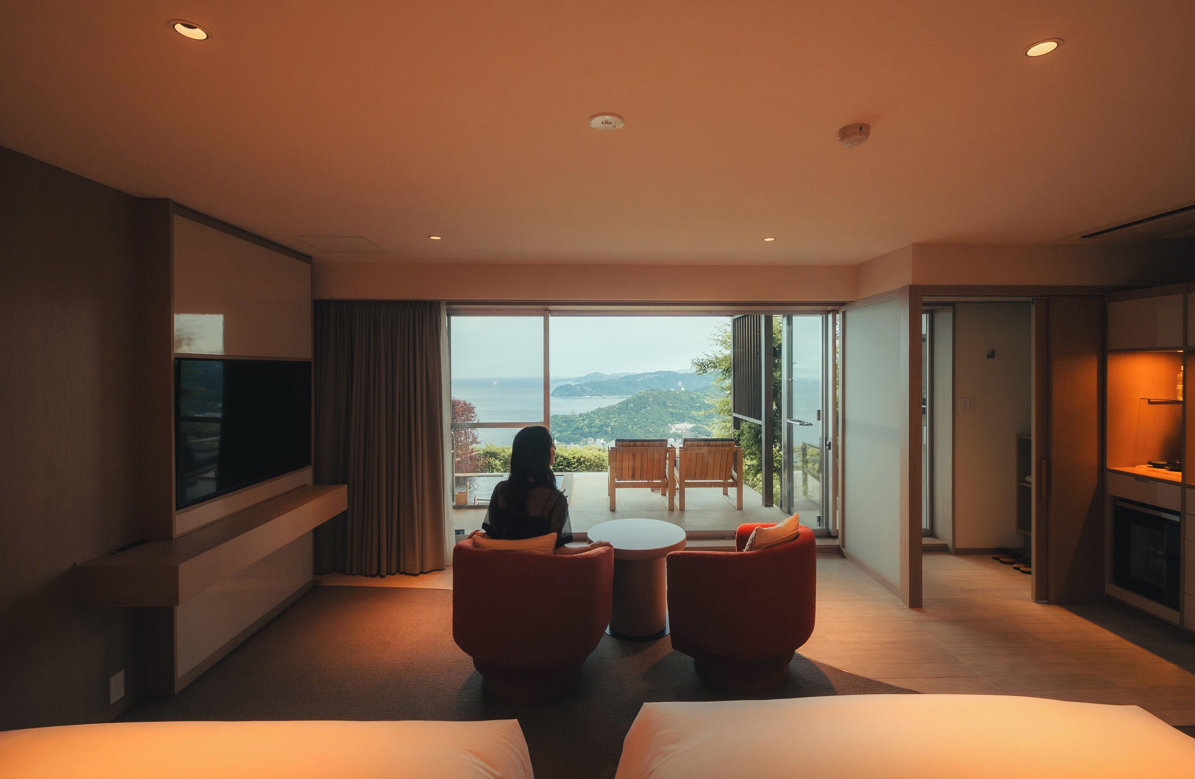 Une chambre d’hôtel dotée d’une grande fenêtre, d’un téléviseur à écran plat, d’un canapé, d’une petite table et d’un lit.