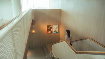 A modern interior with a wooden staircase, a white railing, and a wall-mounted artwork.