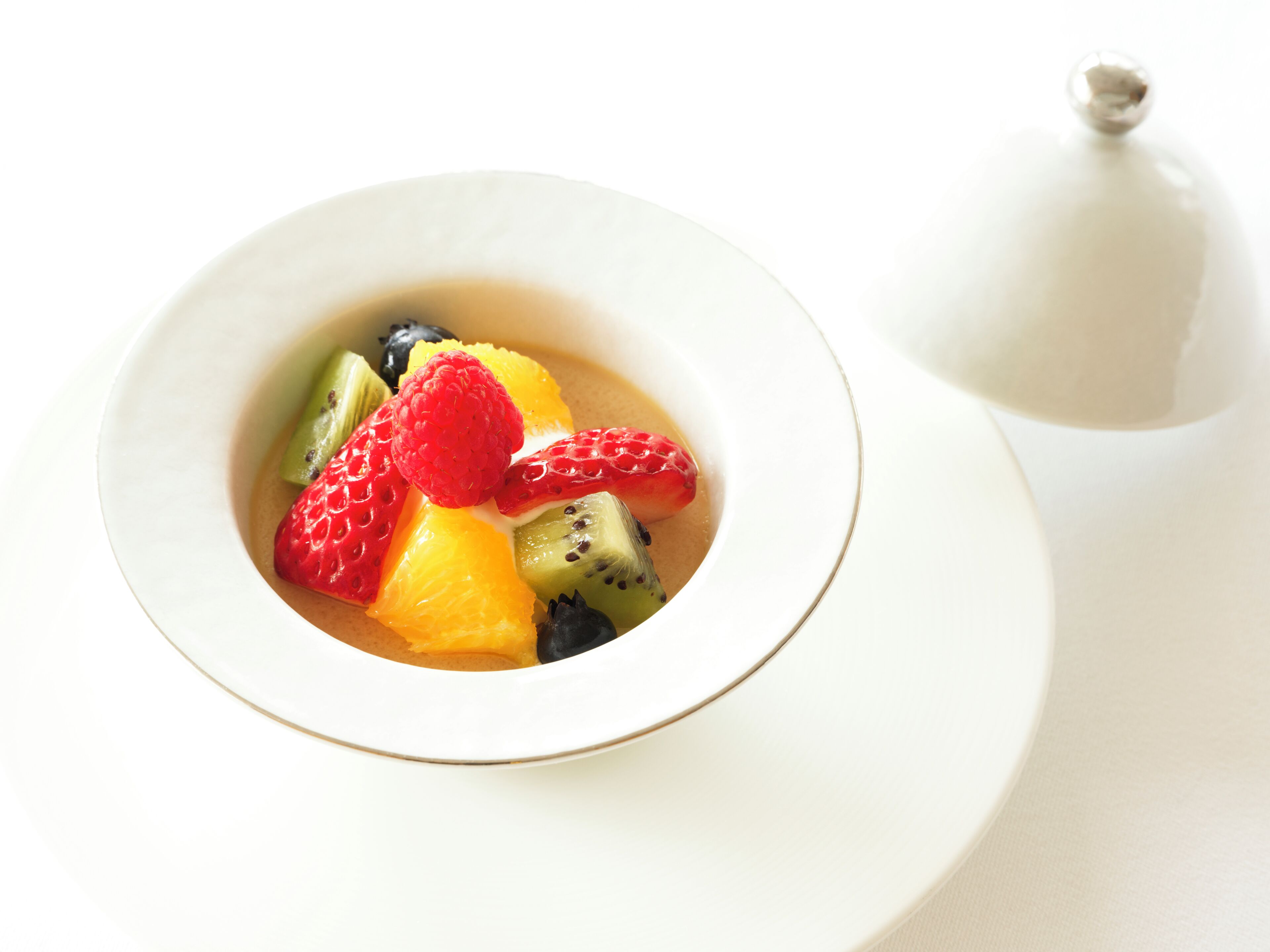A bowl of fruit dessert on a white table.