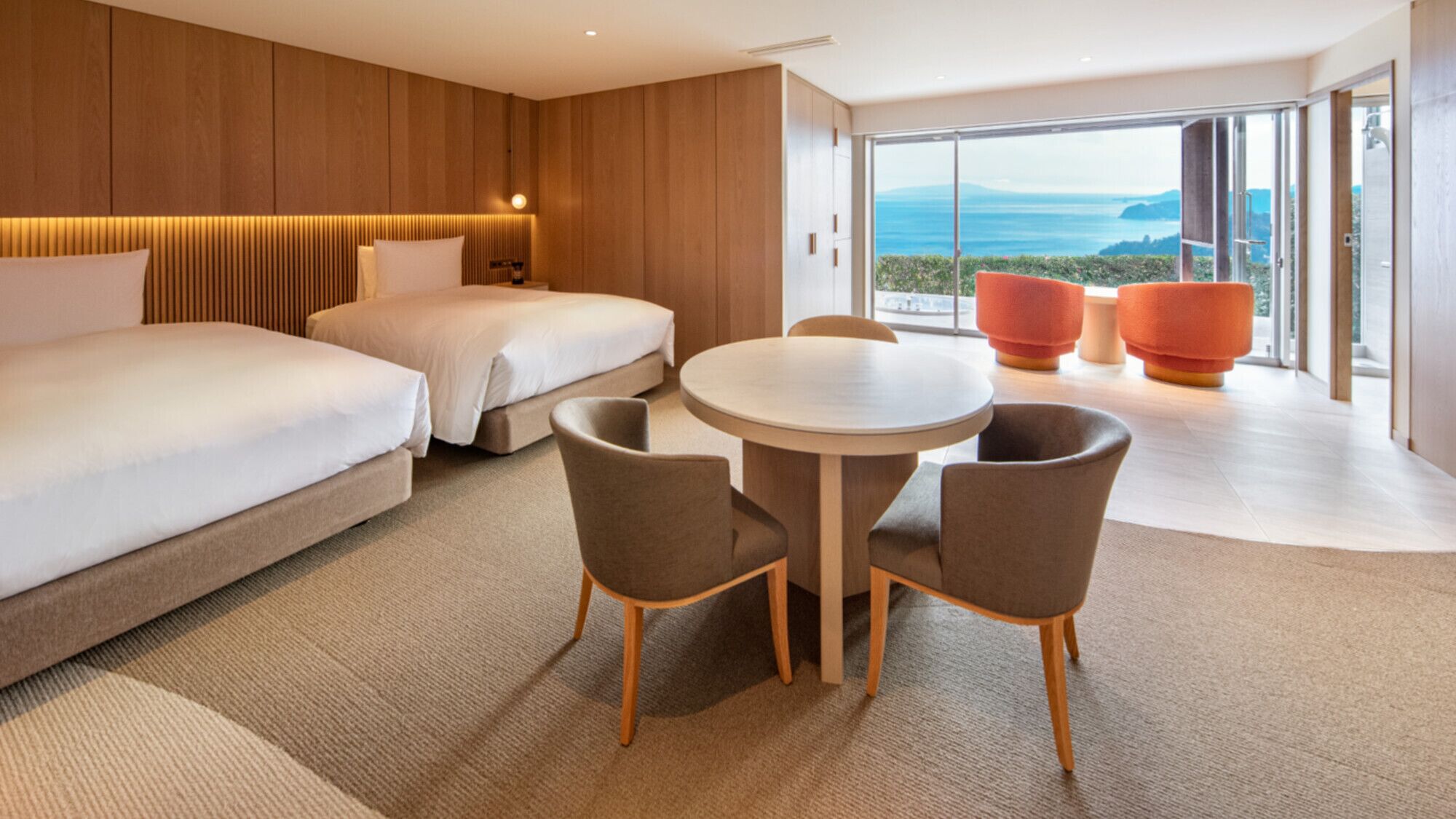Ein Hotelzimmer mit zwei Betten, einem runden Tisch mit Stühlen und Meerblick.